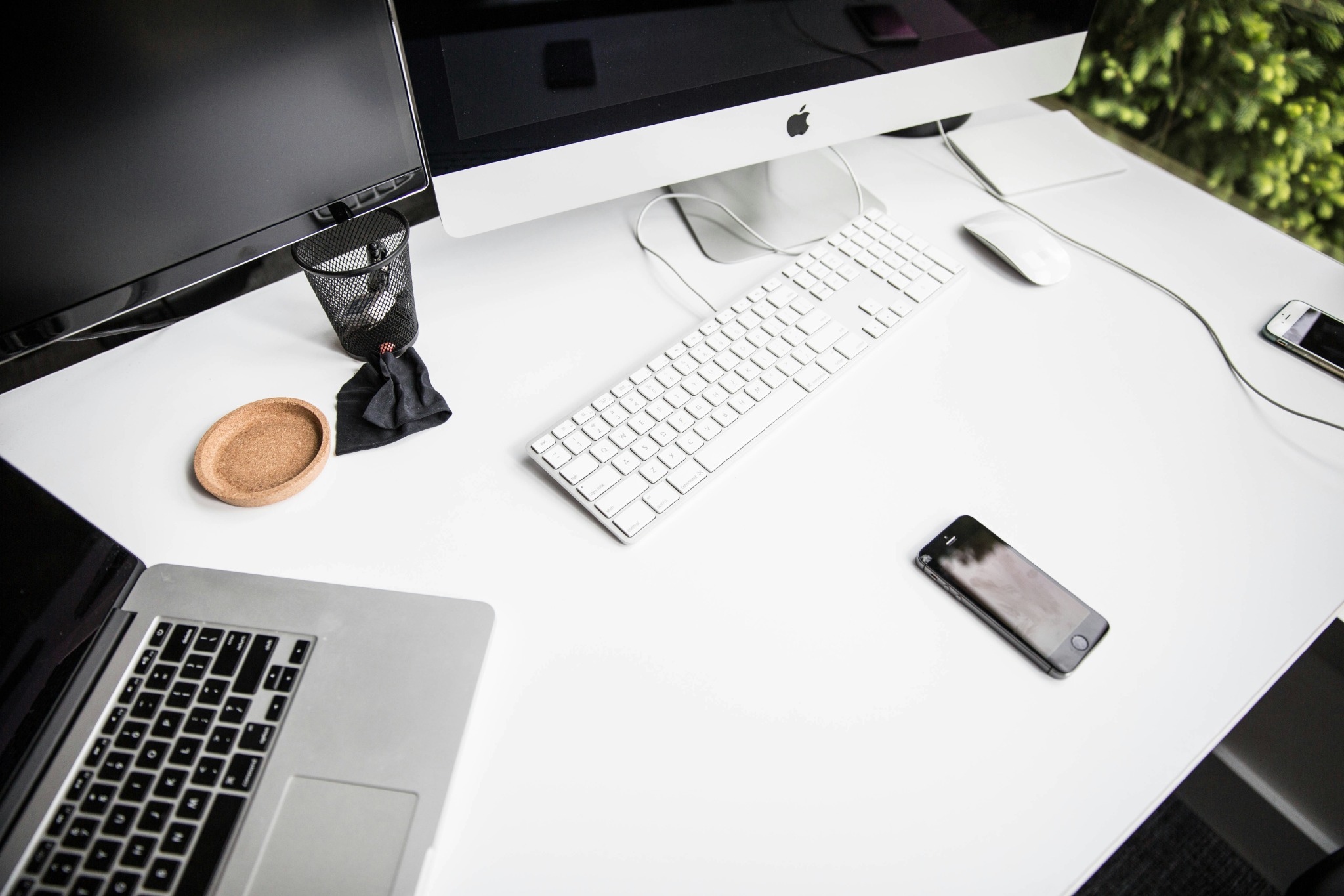 Modern office desk setup with iMac, keyboard, laptop and smartphone on white desk